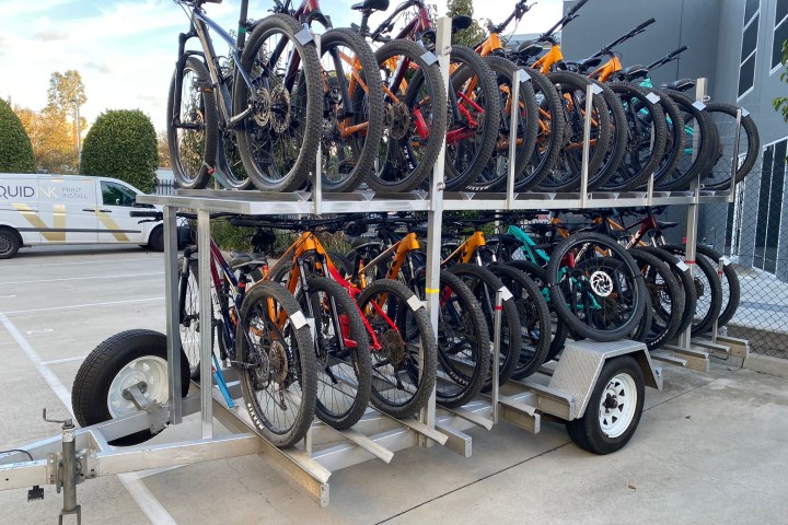 Trailer carrying multiple stacked bicycles in parking lot.